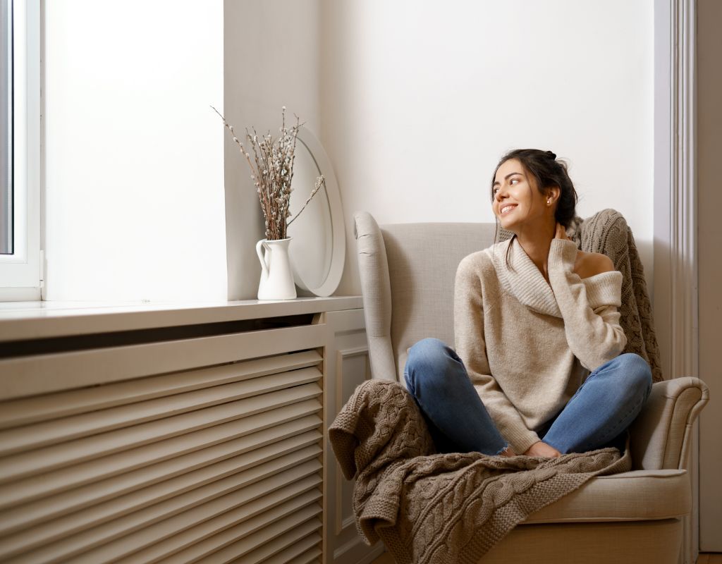 une femme est assise près d'un radiateur