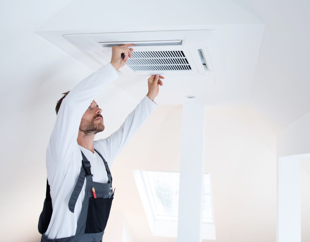 Un homme installant la grille de ventilation sur une climatisation